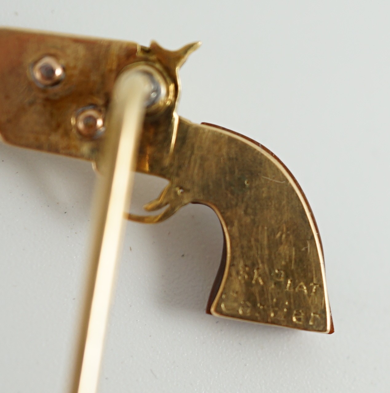 A Cartier 18k gold, platinum and six stone baguette cut diamond set novelty stick pin, modelled and a pistol inscribed 'Peacemaker'